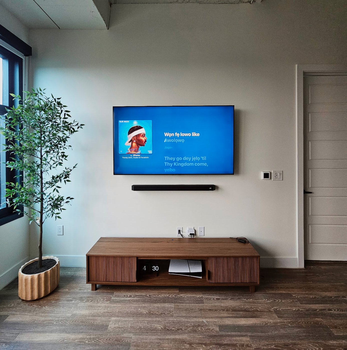 A clean, level TV and soundbar installation in a modern Houston loft with concrete ceiling.