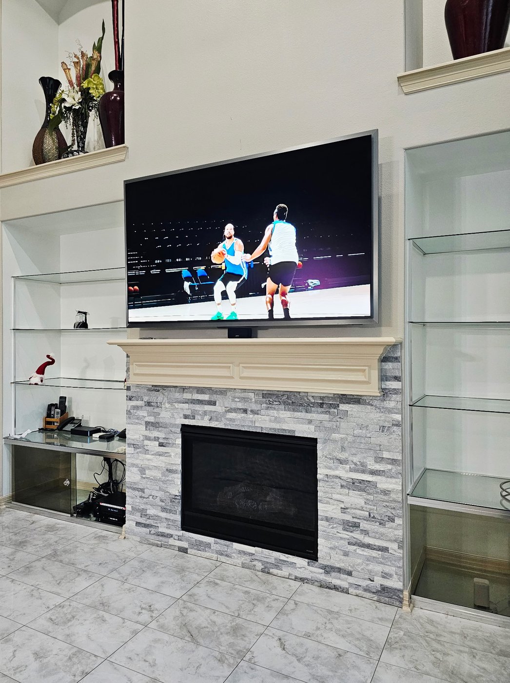 TV mounted above a stone fireplace with custom mantel.