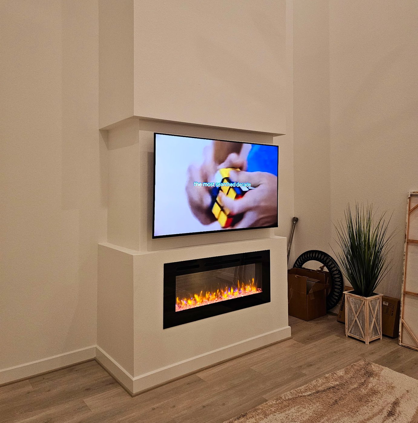 Modern TV installation above a built-in electric fireplace.