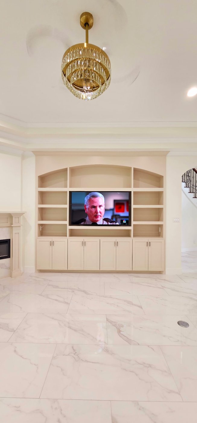 TV installed in a custom built-in unit in a luxury home with marble floors.