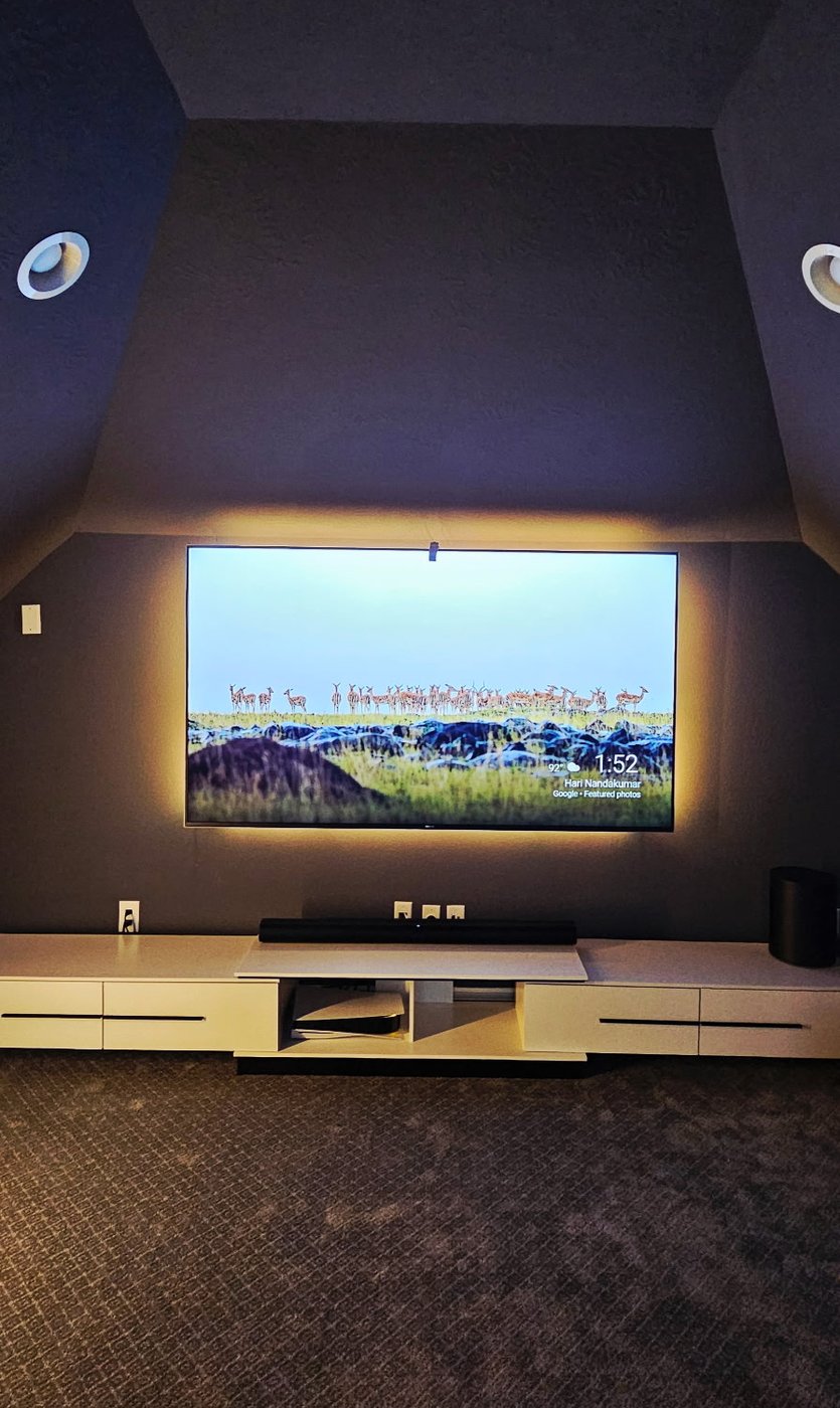 Home theater TV installation with bias lighting in an attic theater room.