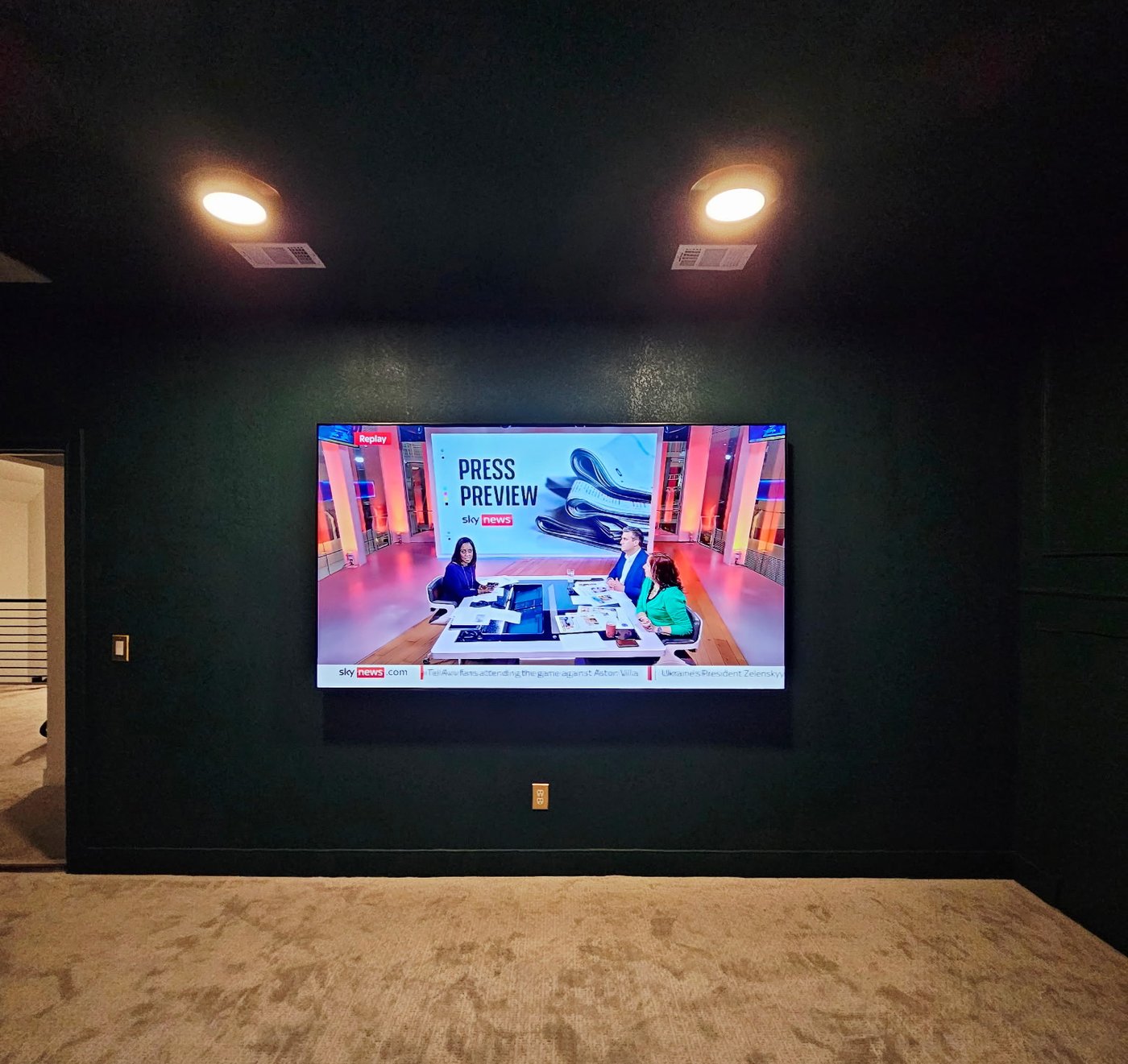 TV installation in a dedicated home theater room with dark green walls.